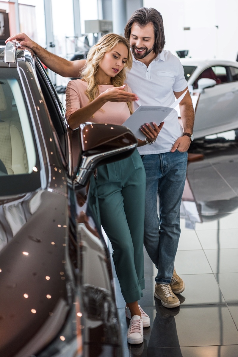 couple-with-catalog-buying-car-at-dealership-salon-2023-11-27-05-31-32-utc